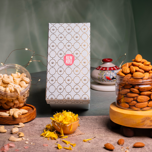 Two jars of nuts with a decorative box in the center on a dark surface.